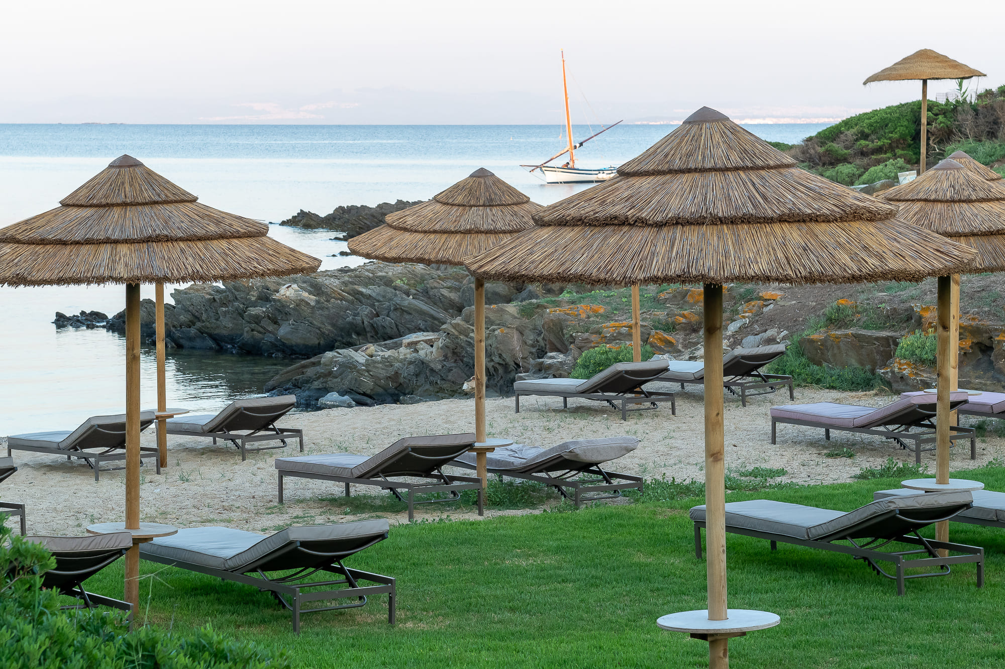Beach and straw umbrellas at Cala Lupo Resort, venue of the BaoNow retreat